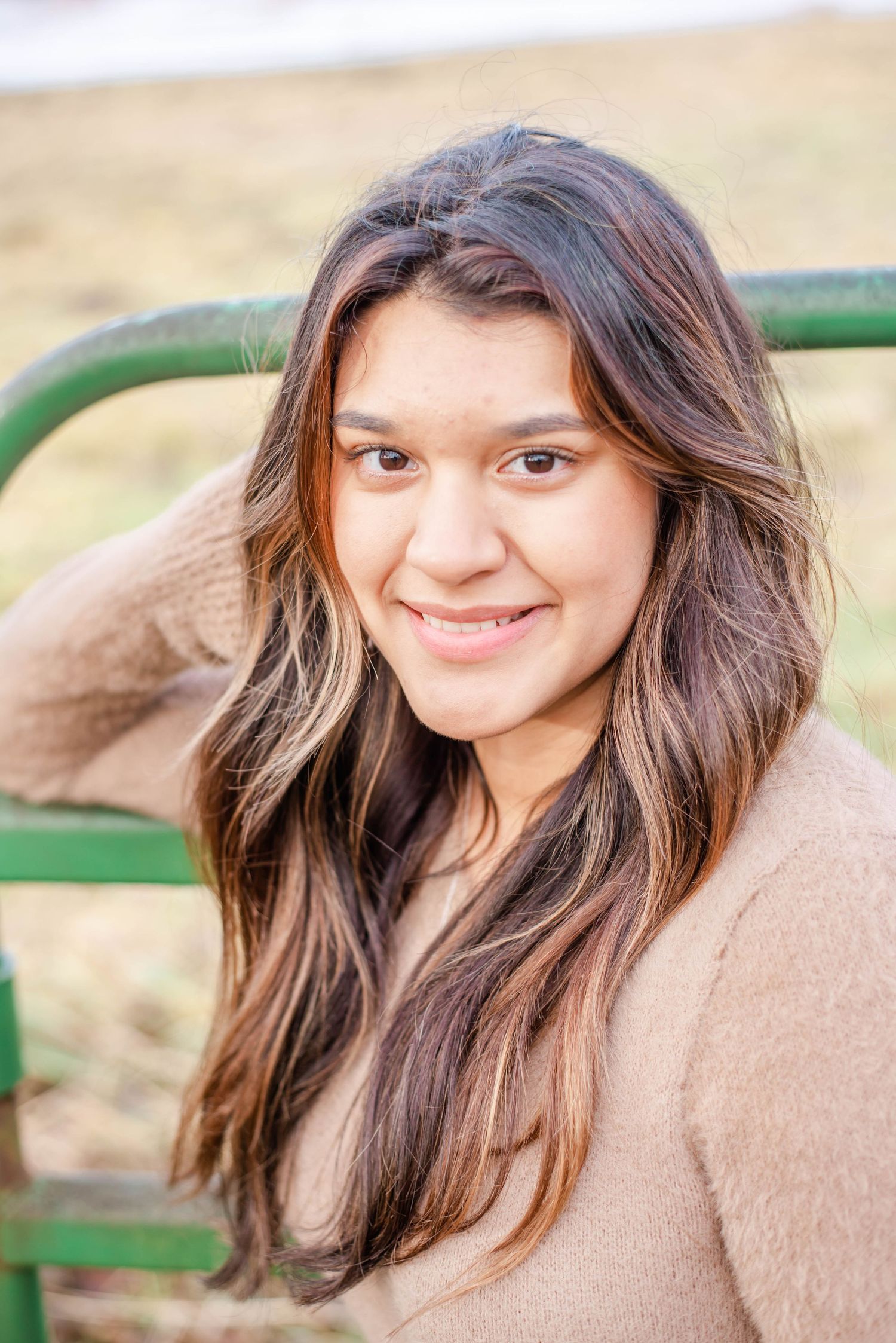 Person in a beige sweater posing outdoors against a natural background.