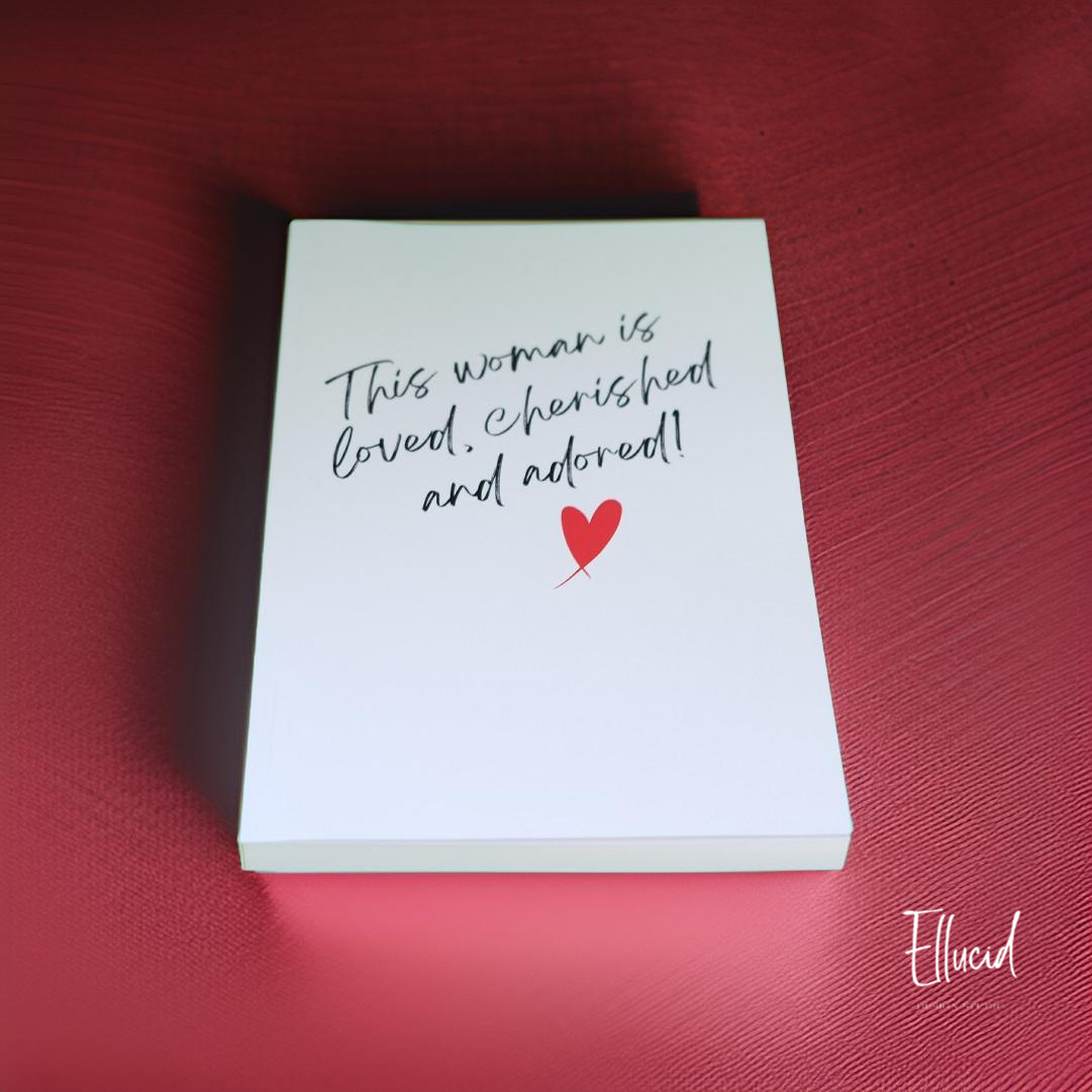 White notecard with handwritten text and small red heart on burgundy background.