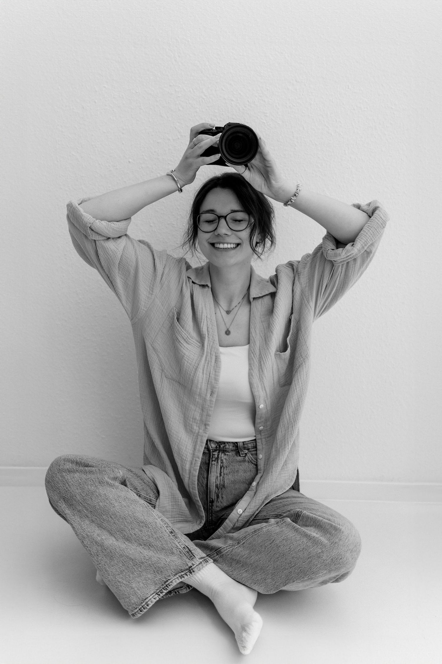 A series of four black and white photos showing someone in casual denim and white attire posing playfully against a wall.