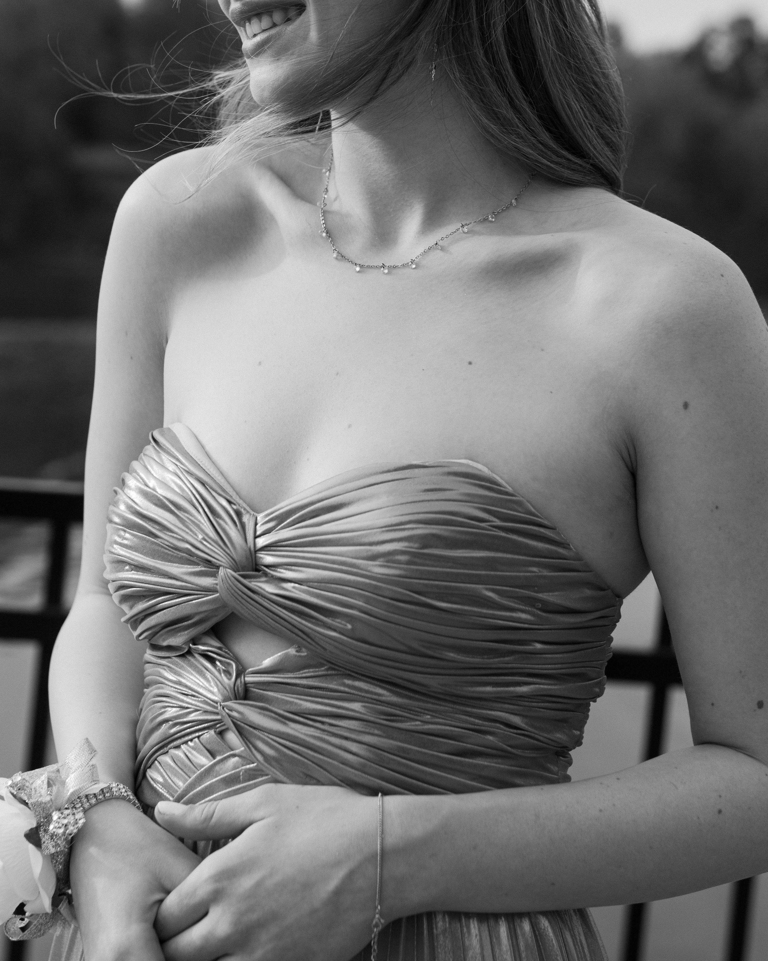 Close-up detail of a ruched strapless pink dress bodice with delicate necklace.