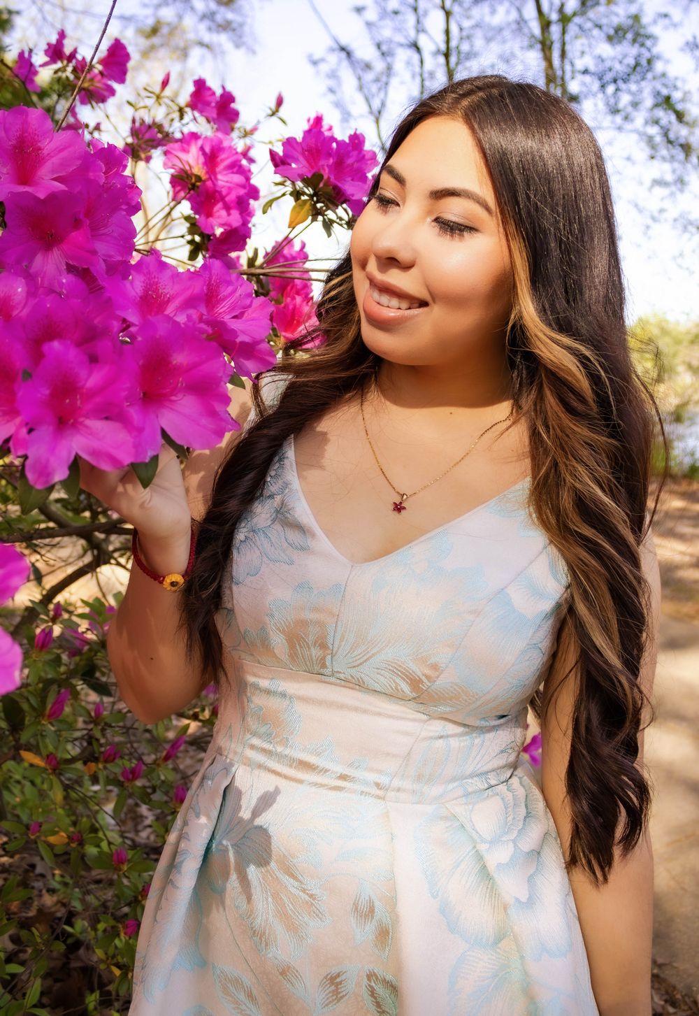 Spring portrait with vibrant pink azalea flowers and light blue floral dress.