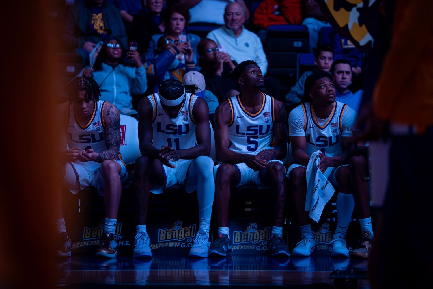 Basketball players and team members sit on bench during game.