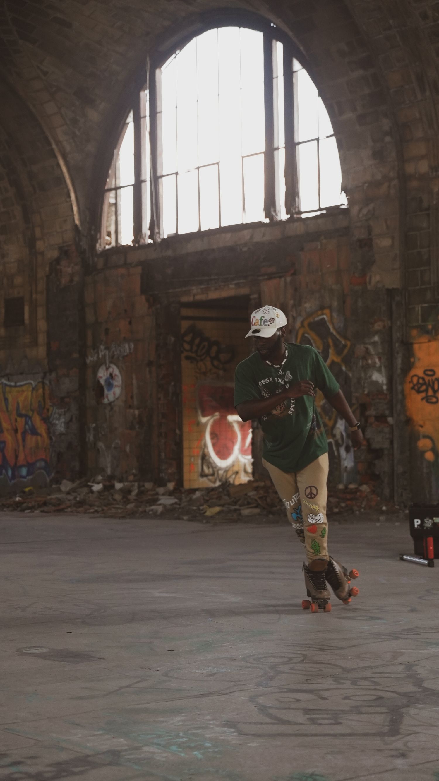 Solo roller skater practices in graffiti-covered abandoned warehouse with arched windows.