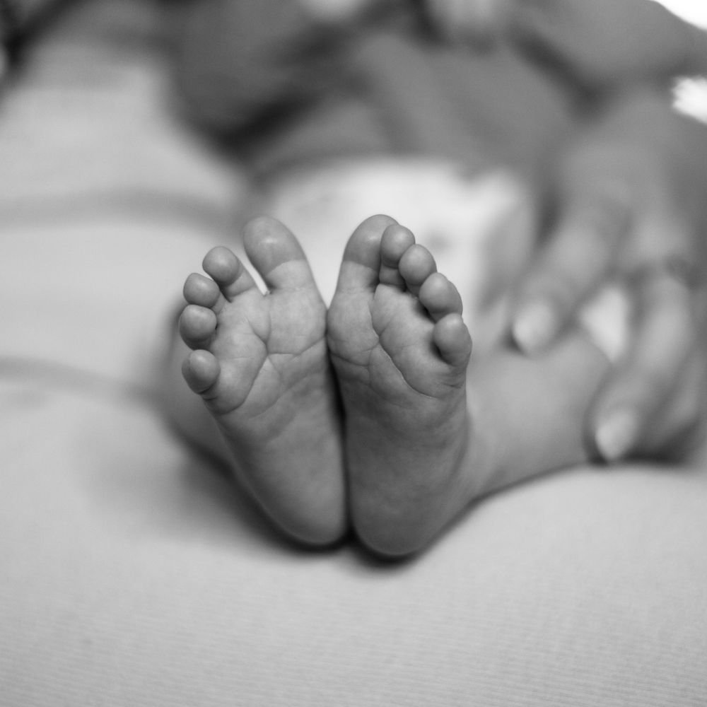 Close-up black and white photo of tiny newborn baby feet.