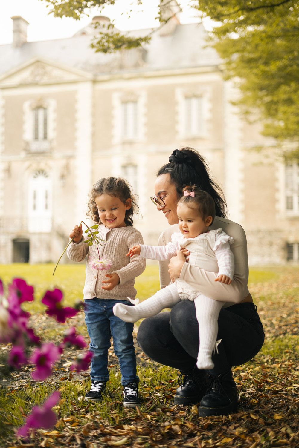 Family enjoying autumn day gathering flowers outside historic building.
