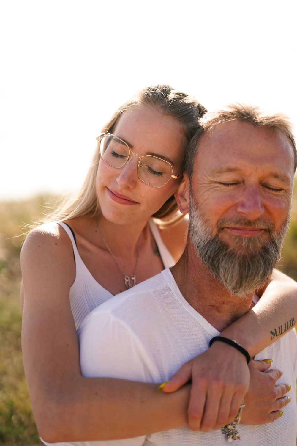 Couple embracing in warm sunlight during a sunset photoshoot.