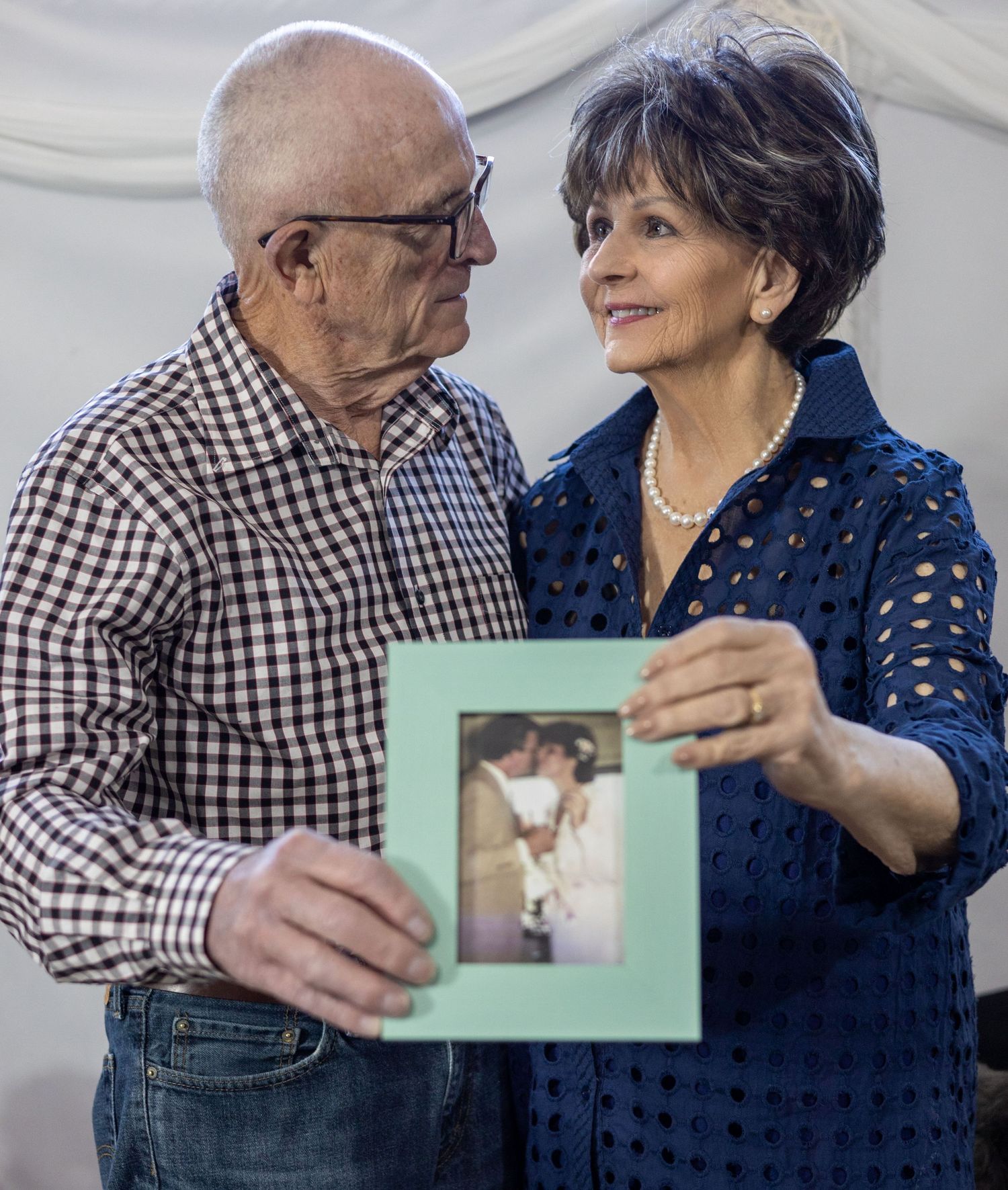 Couple examining mint green picture frame together in series of intimate poses against dark background.