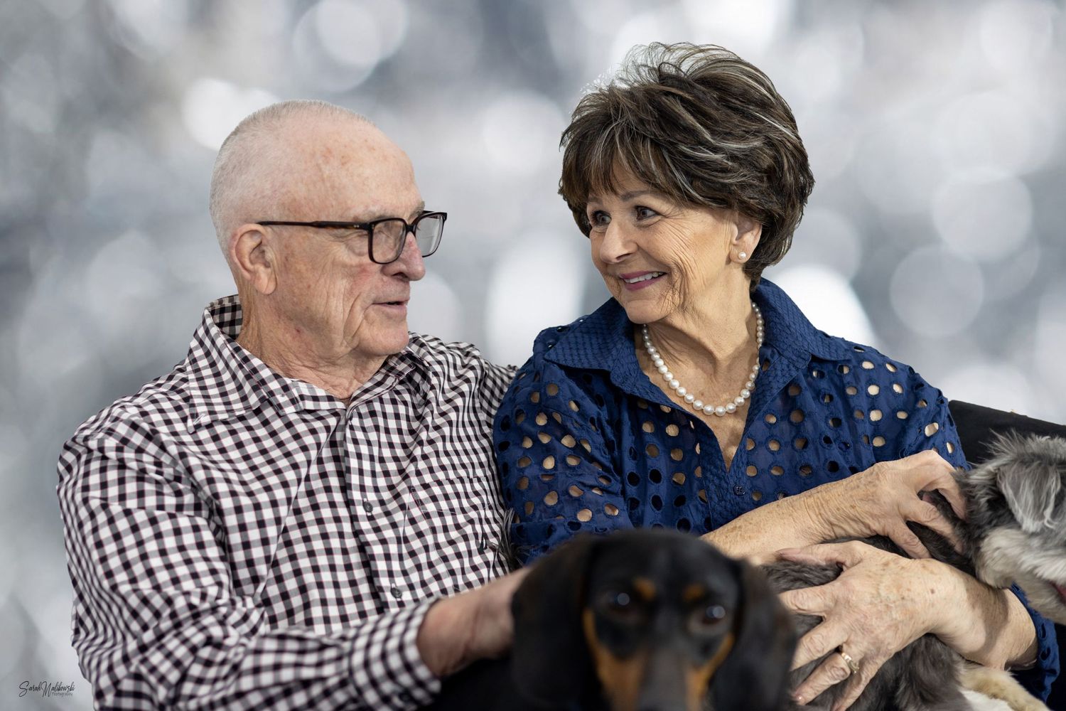 Senior couple sharing tender moments together with their small dog on a couch.
