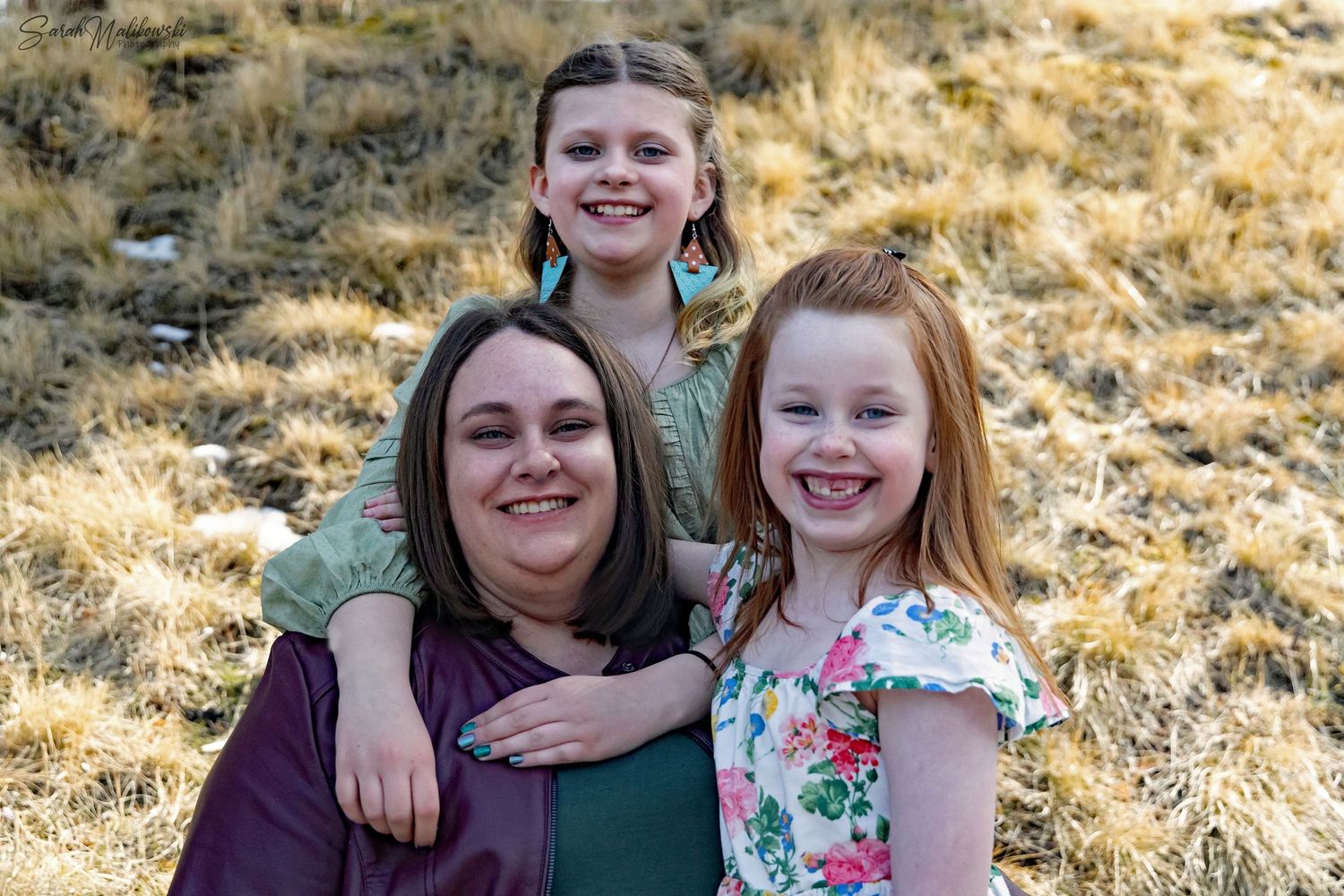 Candid outdoor family portraits in natural lighting with grass background.