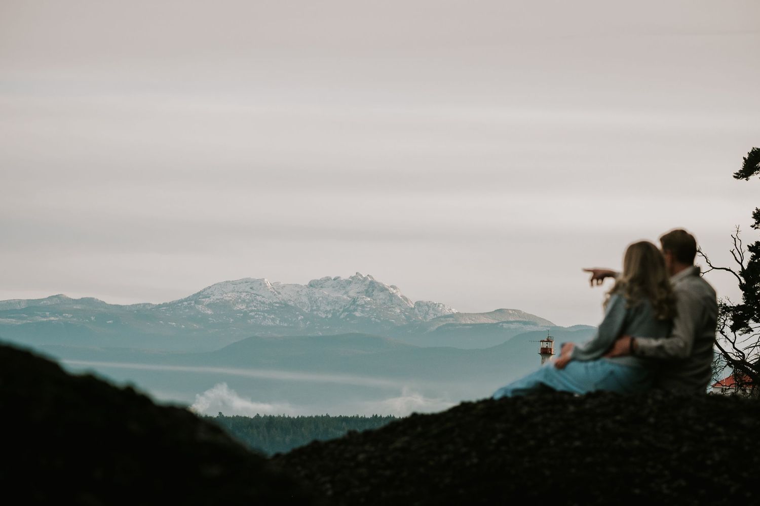 Couple sitting on rock on Denman Island. Professional artistic adventure photo taken by Vancouver Island couple and engagement photographer