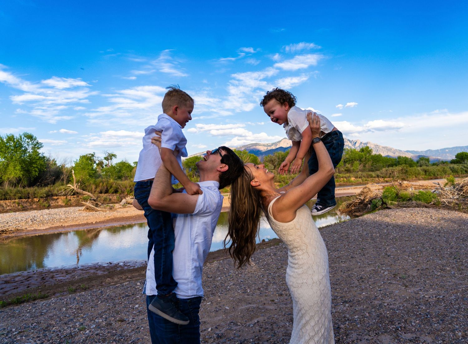 Family playing and having fun together outdoors with blue sky and mountains in background.