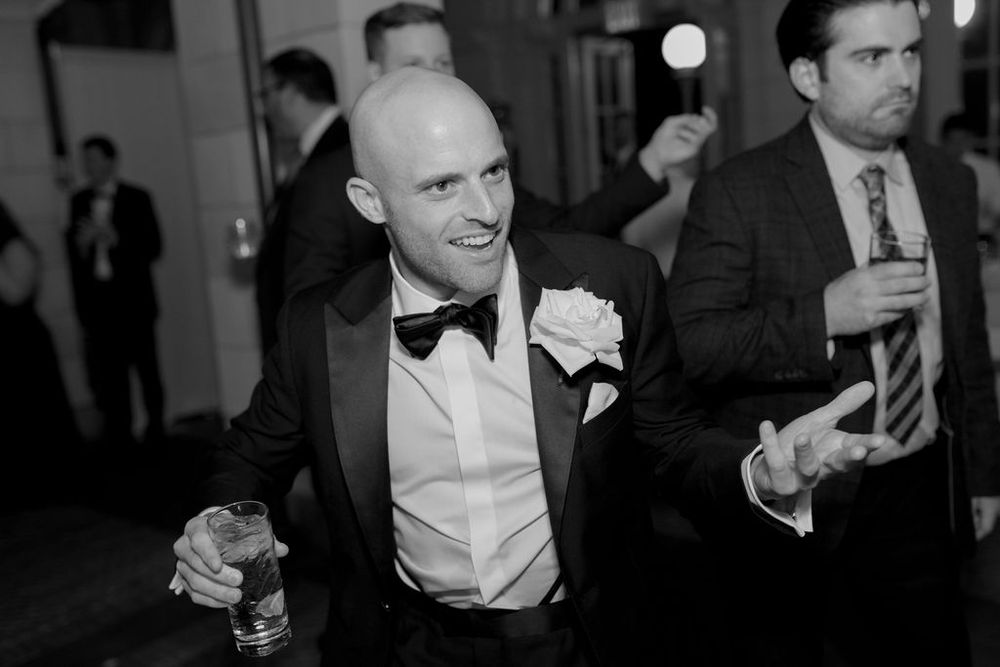 A guest in black tie attire enjoys himself during an elegant evening celebration.