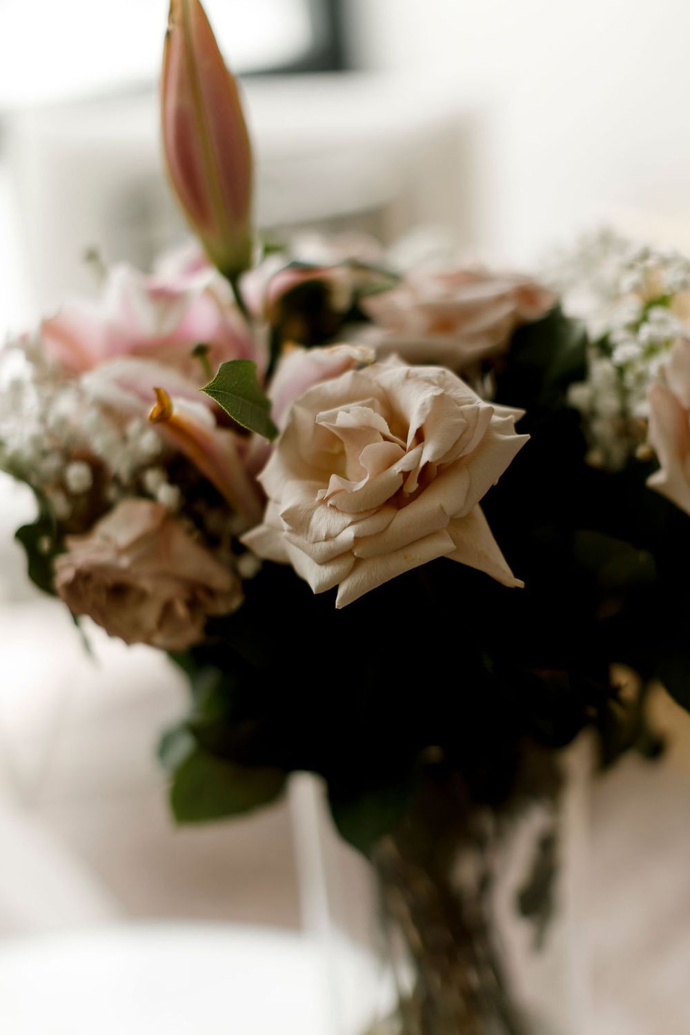 Soft focus image of pale pink roses and white flowers in a glass vase.