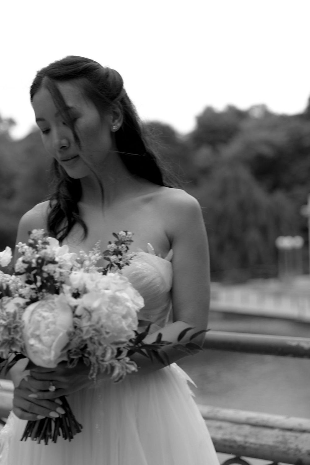 Black and white portrait of bride holding bouquet in strapless wedding gown.