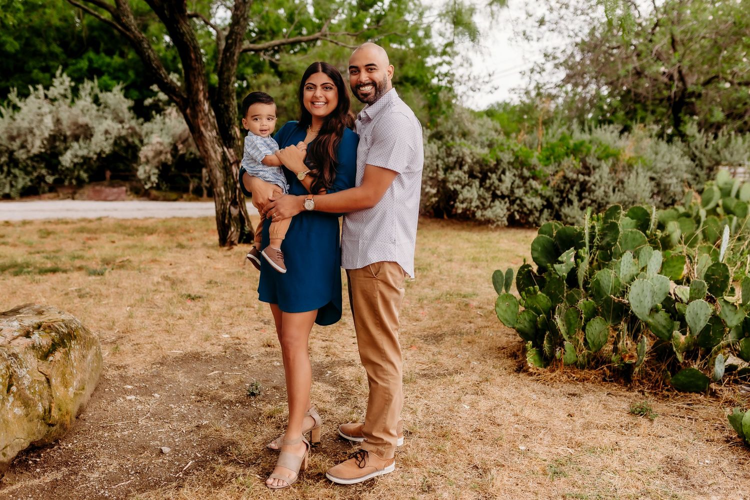 Family portrait with toddler in desert landscape with cactus and trees.