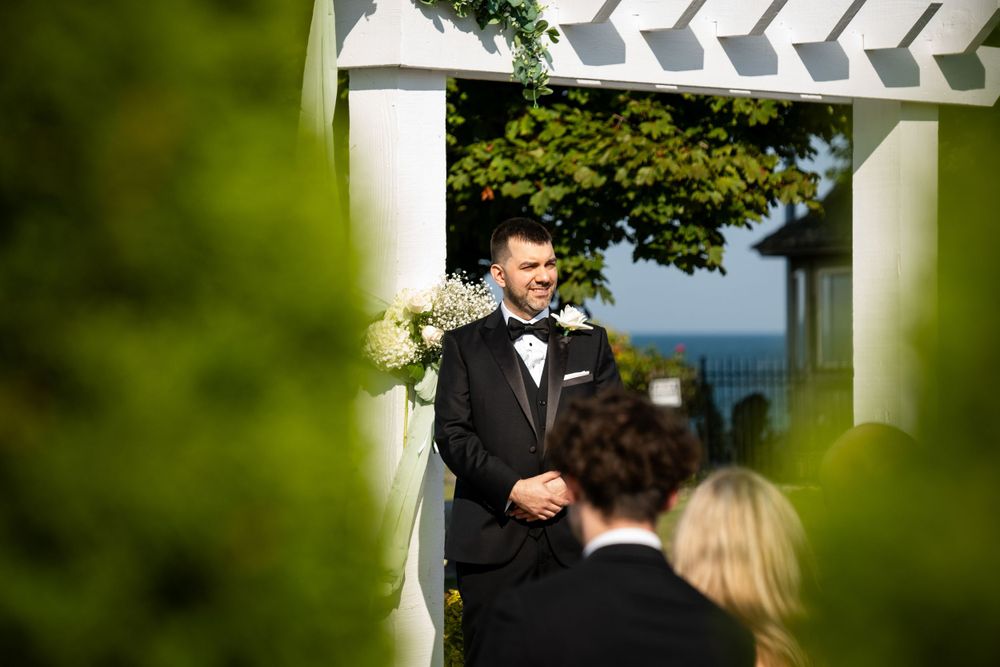 An outdoor wedding ceremony under a white pergola with ocean views.