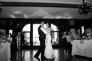 Black and white photo of a couple sharing their first dance at a wedding reception.
