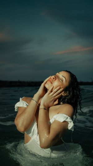 Artistic water portrait with white dress at dusk showing emotional expression.