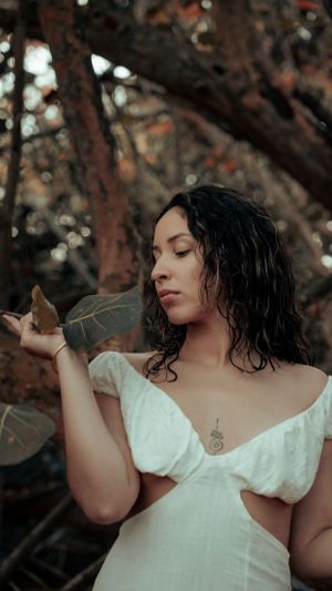 Artistic portrait in white dress with wet curly hair in a moody forest setting.