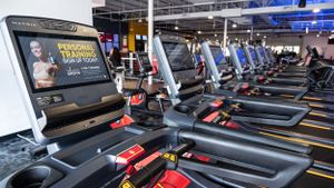 Modern gym interior with line of treadmills featuring digital display screens.