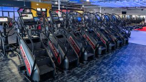 Row of elliptical machines in a commercial gym with blue flooring.