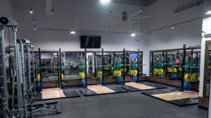 Modern fitness gym interior with weight training equipment, platforms, and overhead lighting.