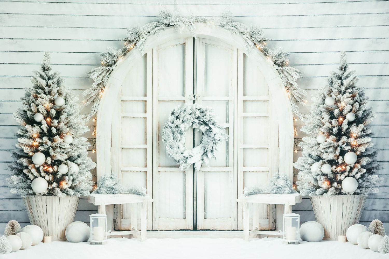 White winter wedding backdrop with arched doorway, flocked trees and holiday ornaments.
