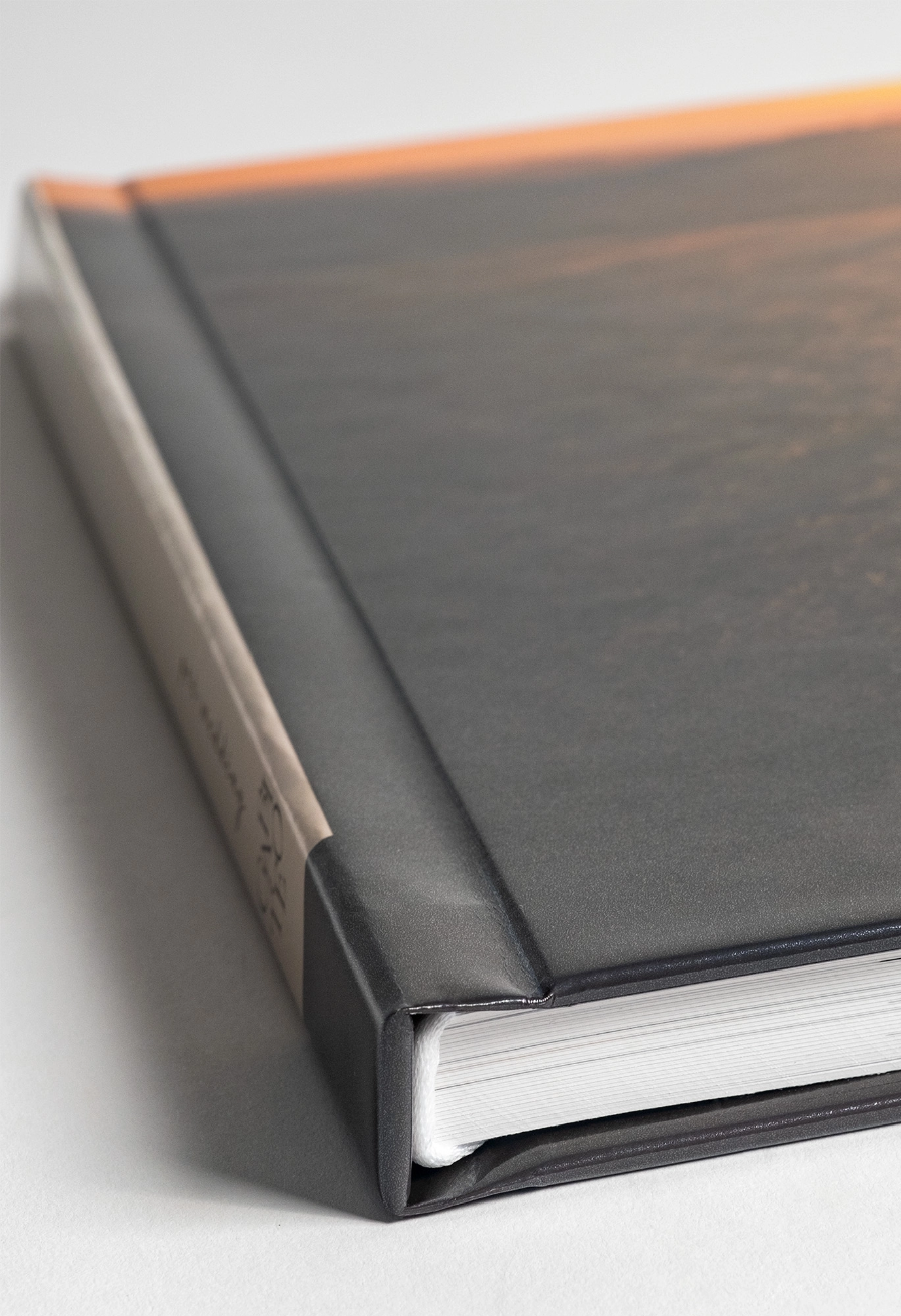Corner detail of a black leather-bound book with white pages visible.