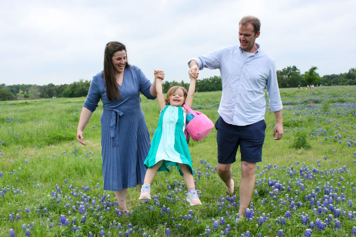 Family enjoys playful moment together in blooming bluebonnet field.
