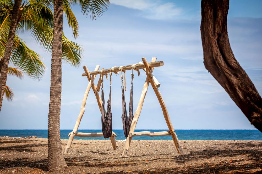 a beach scene featuring swings and turquoise water in the late afternoon sun in the Kona Village resort on the big island of Hawaii