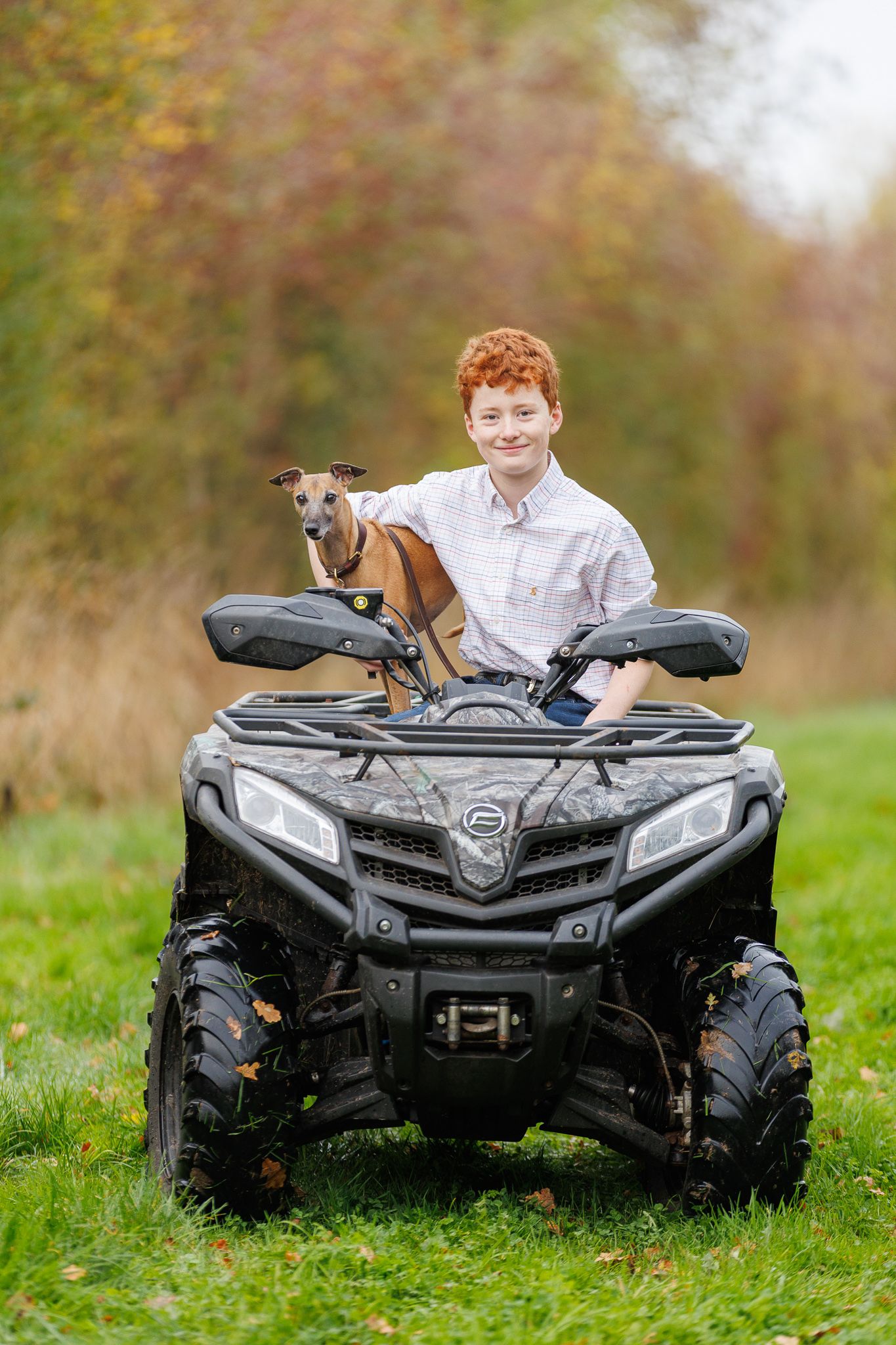 Black ATV parked on grass with small dog sitting on the seat.