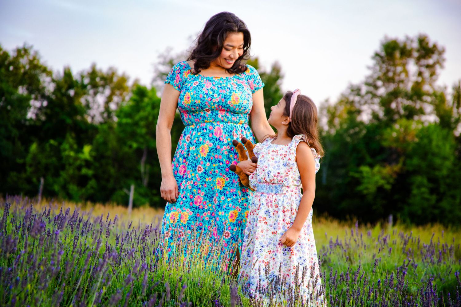 Mother and daughter walking through a blooming lavender field at sunset.