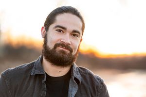 Portrait of a person with beard at sunset wearing casual attire outdoors.