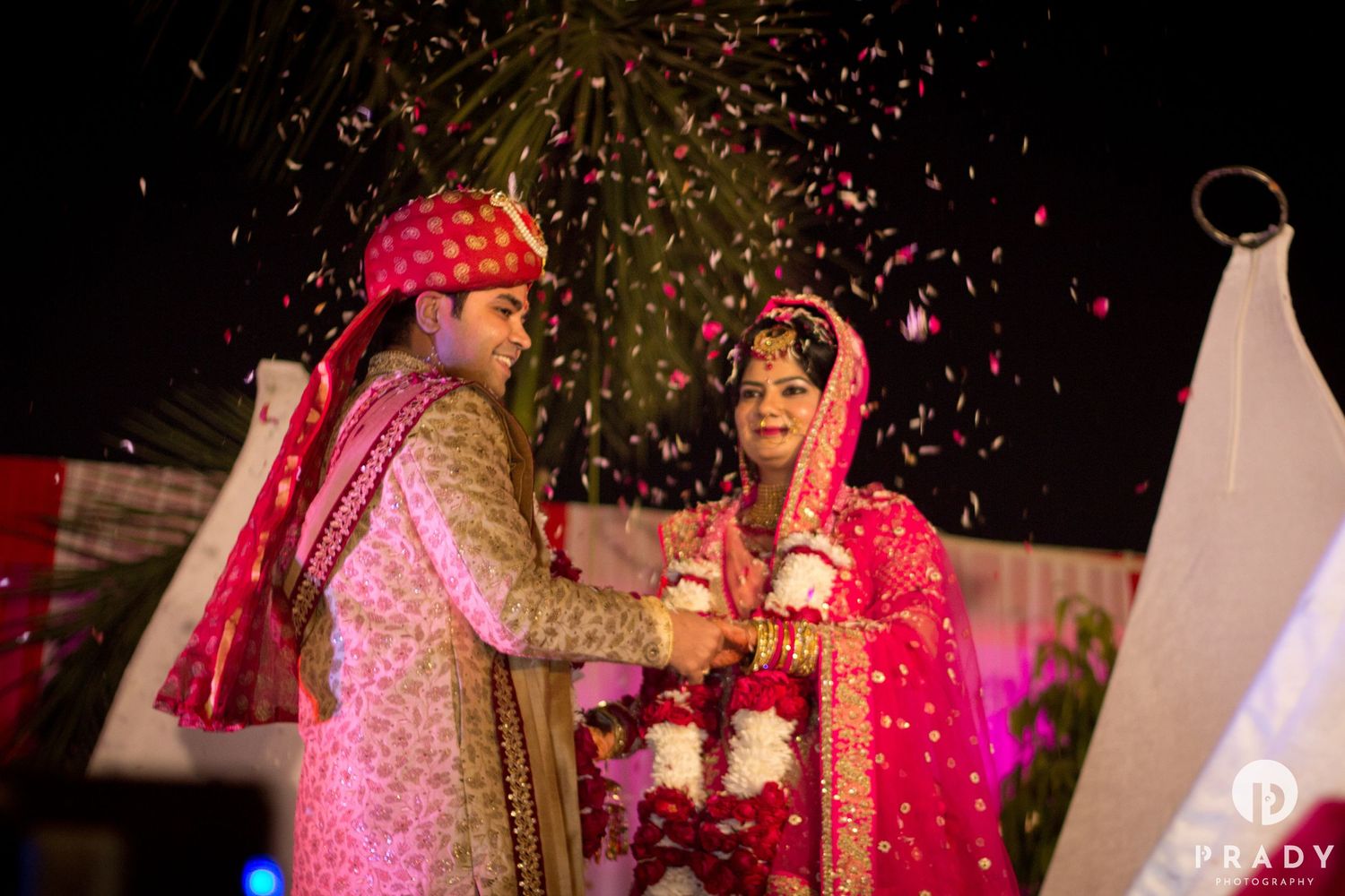 Traditional Indian wedding ceremony with pink attire and falling confetti.