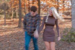 Blurred motion shot of couple walking together in autumn forest.