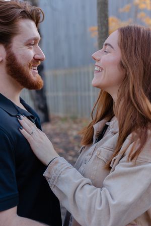 Two people share a joyful laugh while embracing in an intimate outdoor moment.