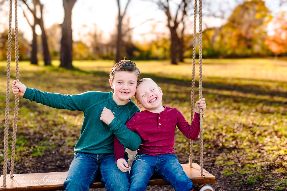 Brothers on a swing in the fall at coal creek farm in jenks, oklahoma