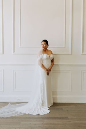 Bride standing by wall. Wedding photography by Samantha Bateman.