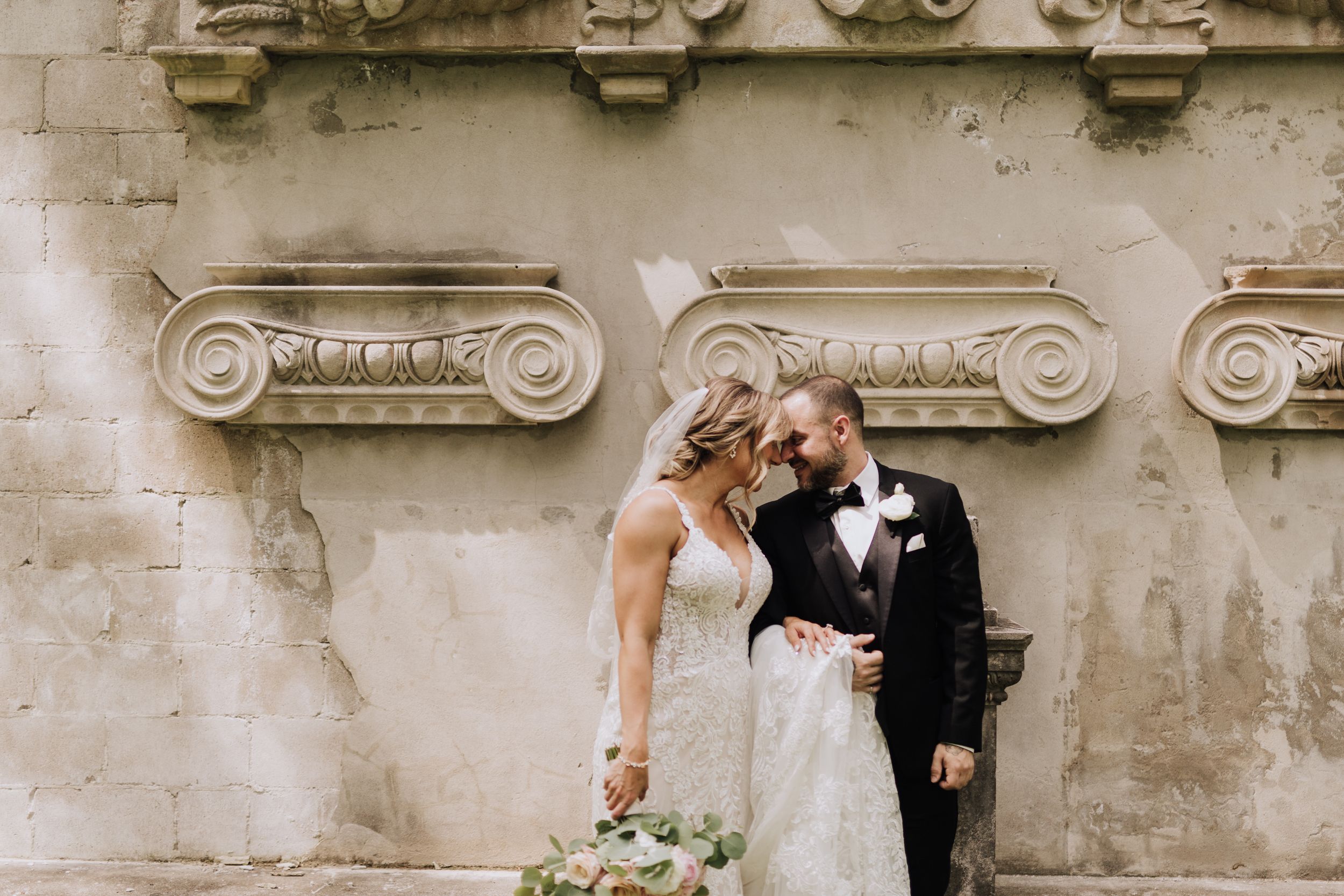 Bride and Groom by wall. Wedding photography by Samantha Bateman.