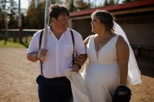 Bride and bride walking in baseball field. Photography by Samantha Bateman. Nova Scotia wedding photographer.