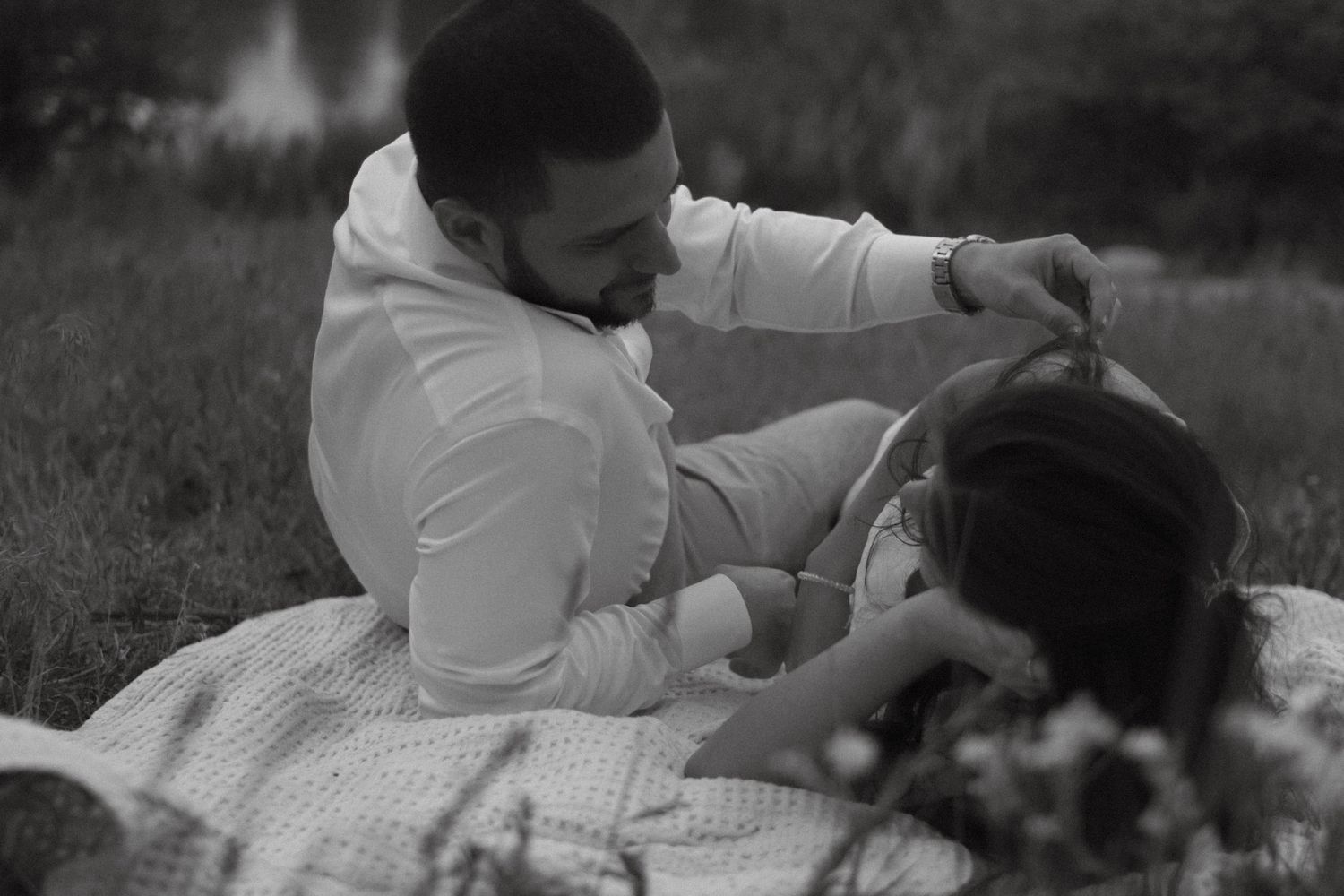 Black and white image of engaged couple sharing an intimate moment while relaxing on a picnic blanket outdoors. Timeless, romantic, Colorado