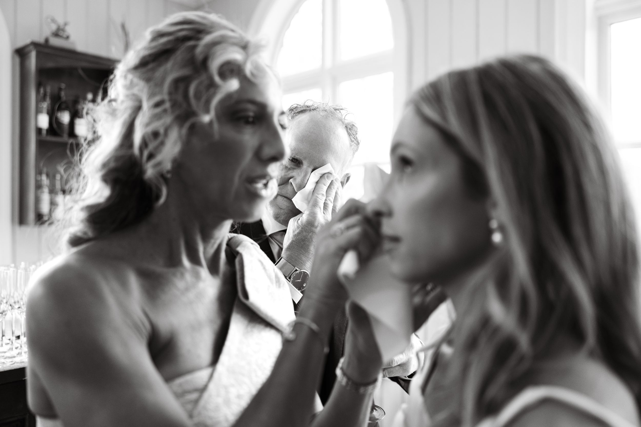 Black and white photo of two people getting ready in front of a mirror.