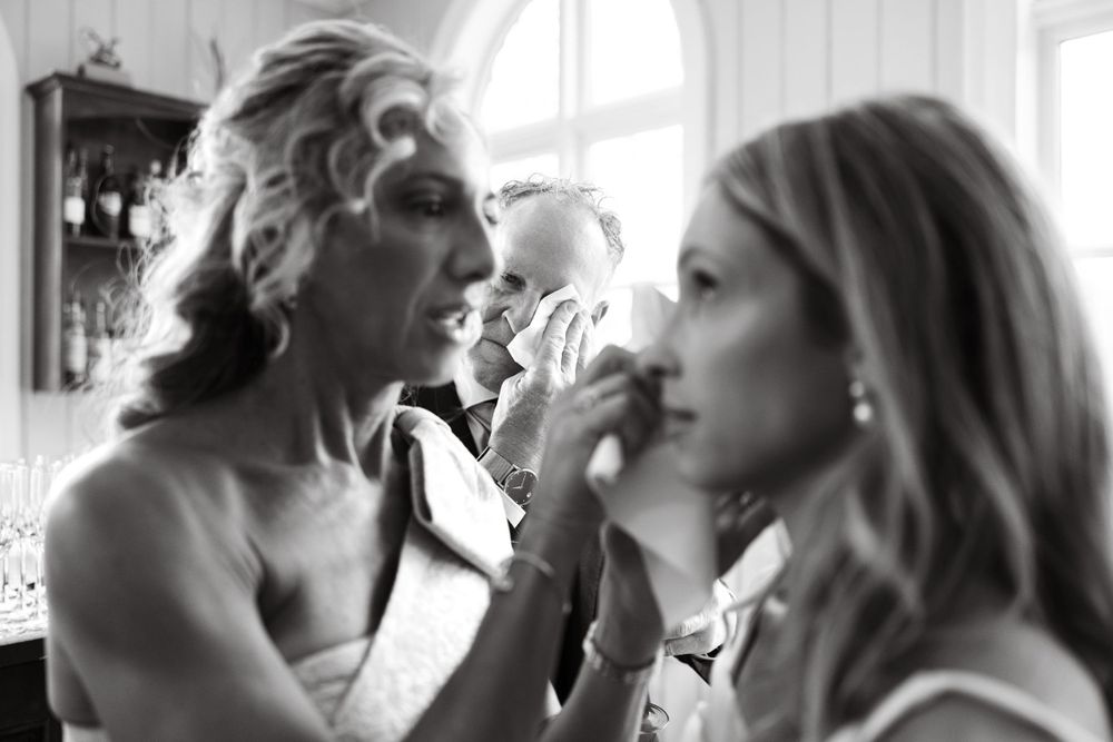 Black and white photo of two people getting ready in front of a mirror.