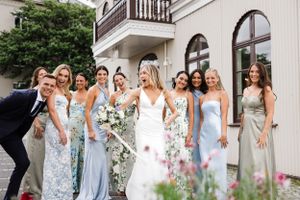 A wedding party poses together on steps with bridesmaids in blue and floral dresses.
