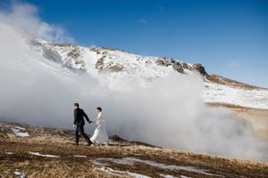 A couple walking through misty mountains in wedding attire during a winter photoshoot.
