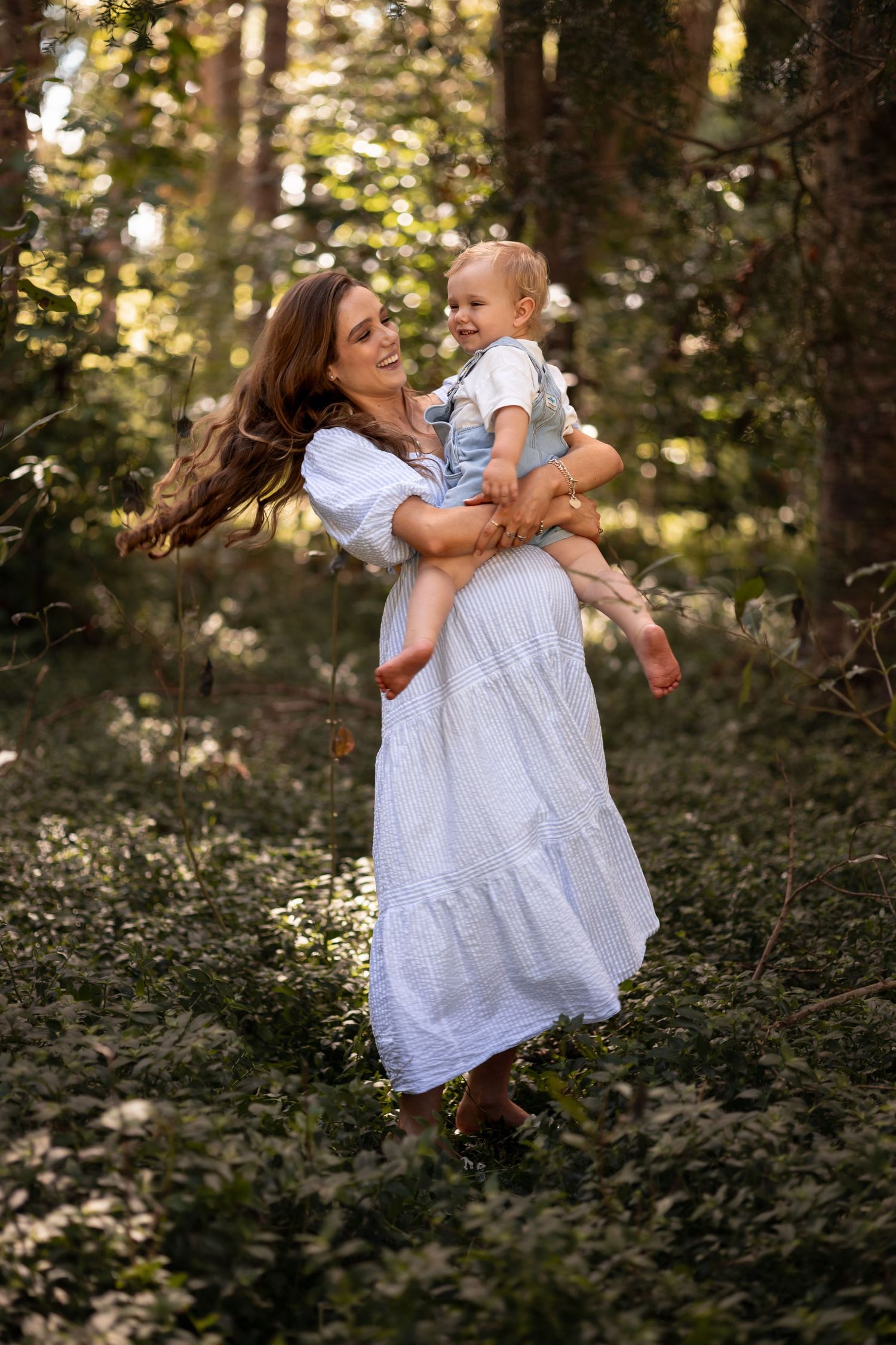 Pregnant mother holding toddler as they swing around in the forest. Maternity Photoshoot package. CL Photography
