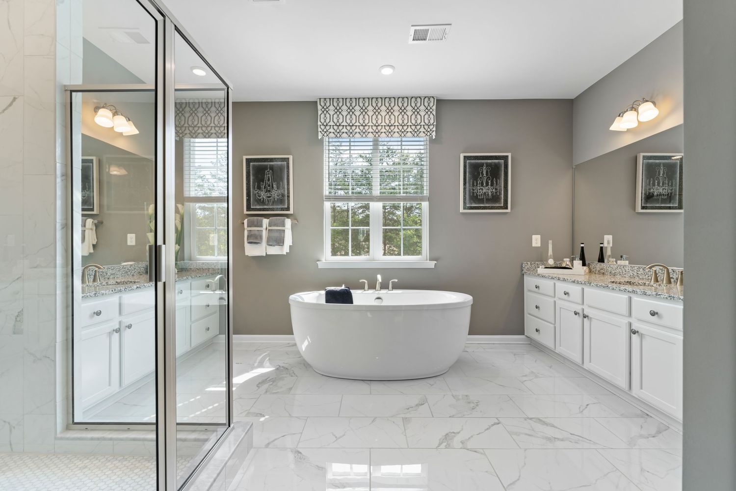 Spacious master bathroom with freestanding soaking tub, double vanity and large windows.