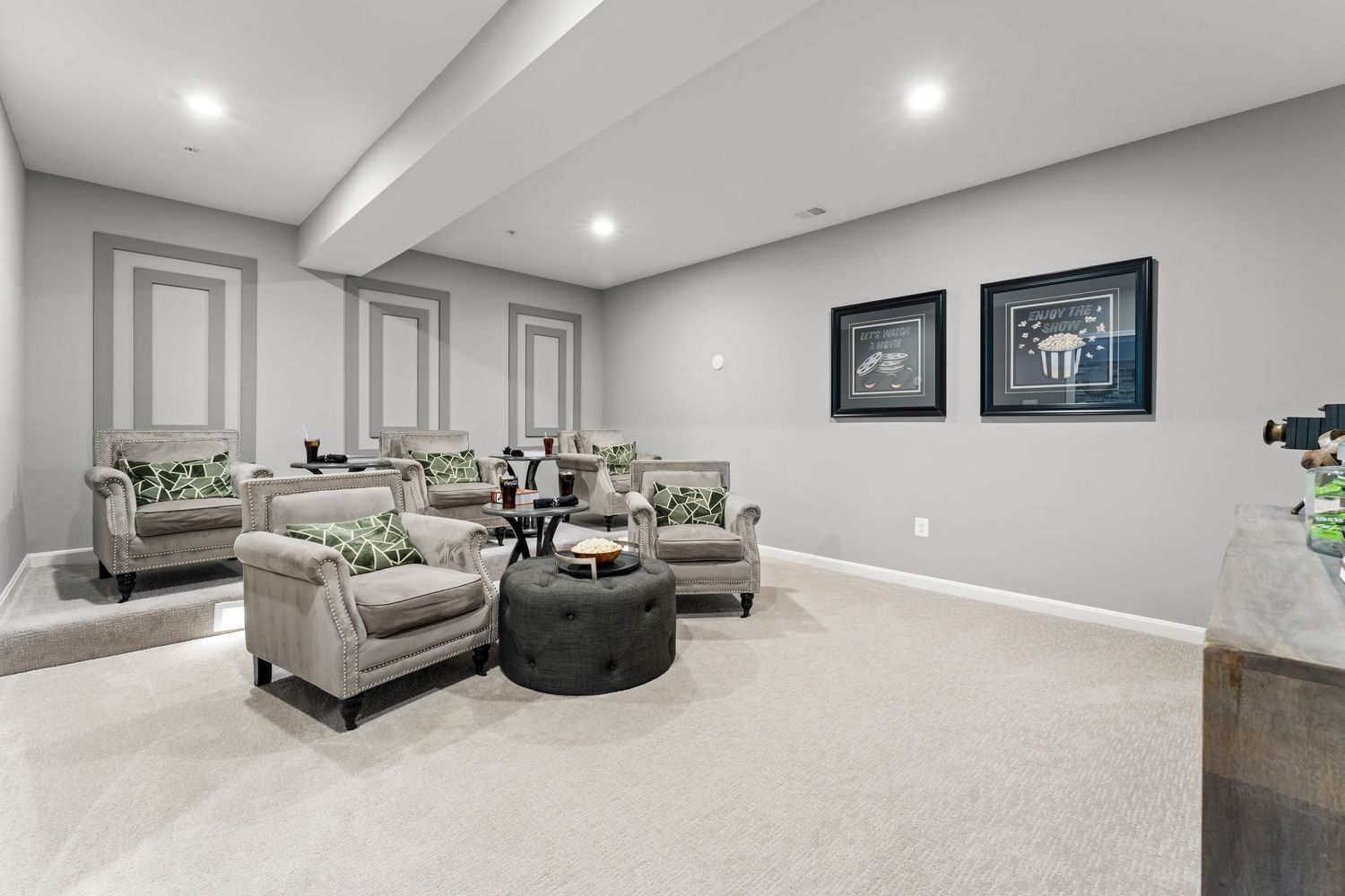 Modern finished basement recreation room with recessed lighting and neutral decor.