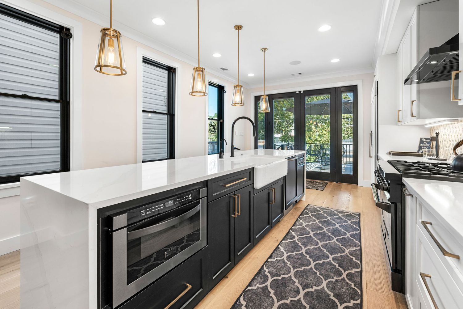 Contemporary kitchen with black base cabinets, white upper cabinets, and geometric runner rug.