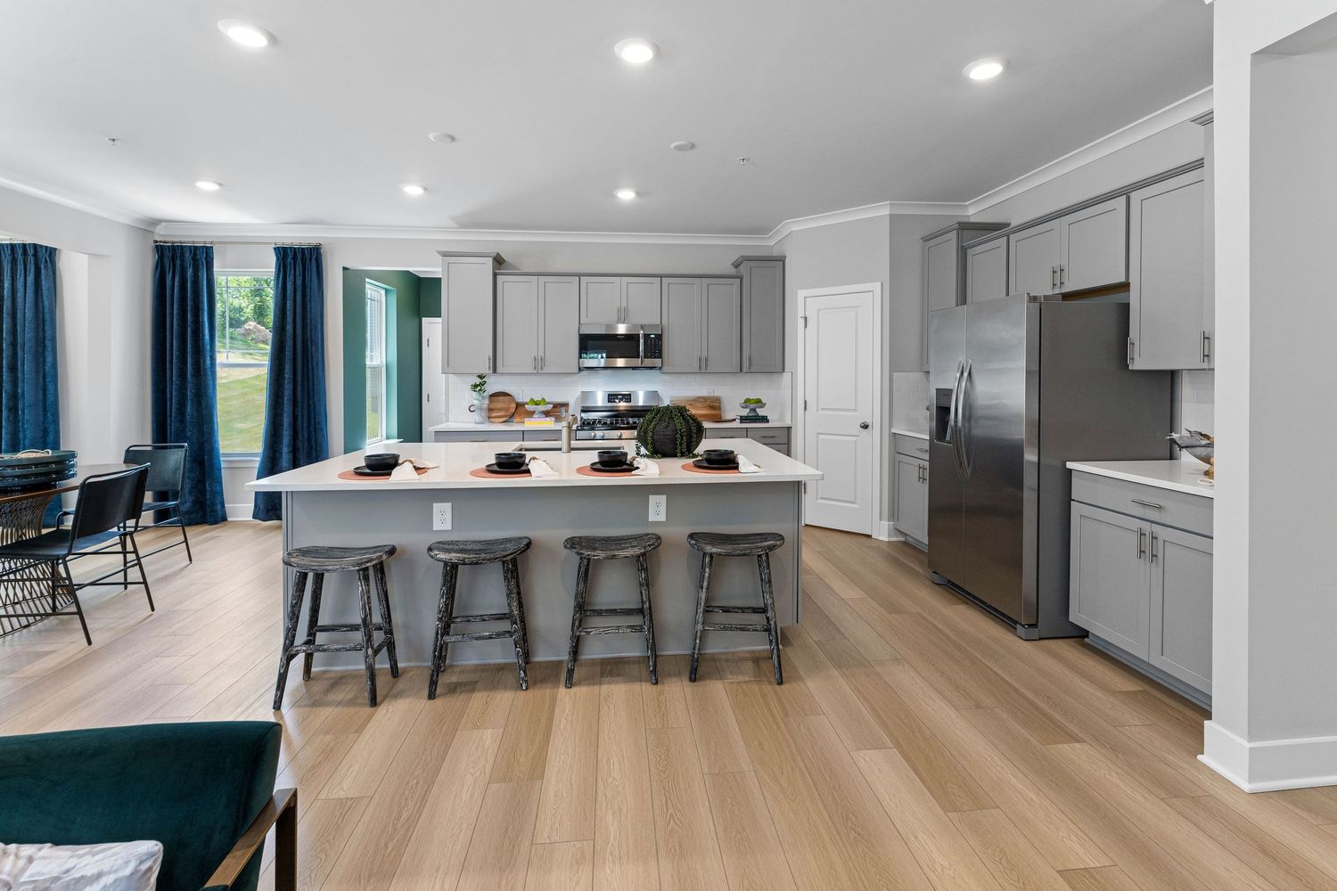 Modern open concept kitchen with gray cabinets, hardwood floors and blue accents features a spacious island with bar seating.